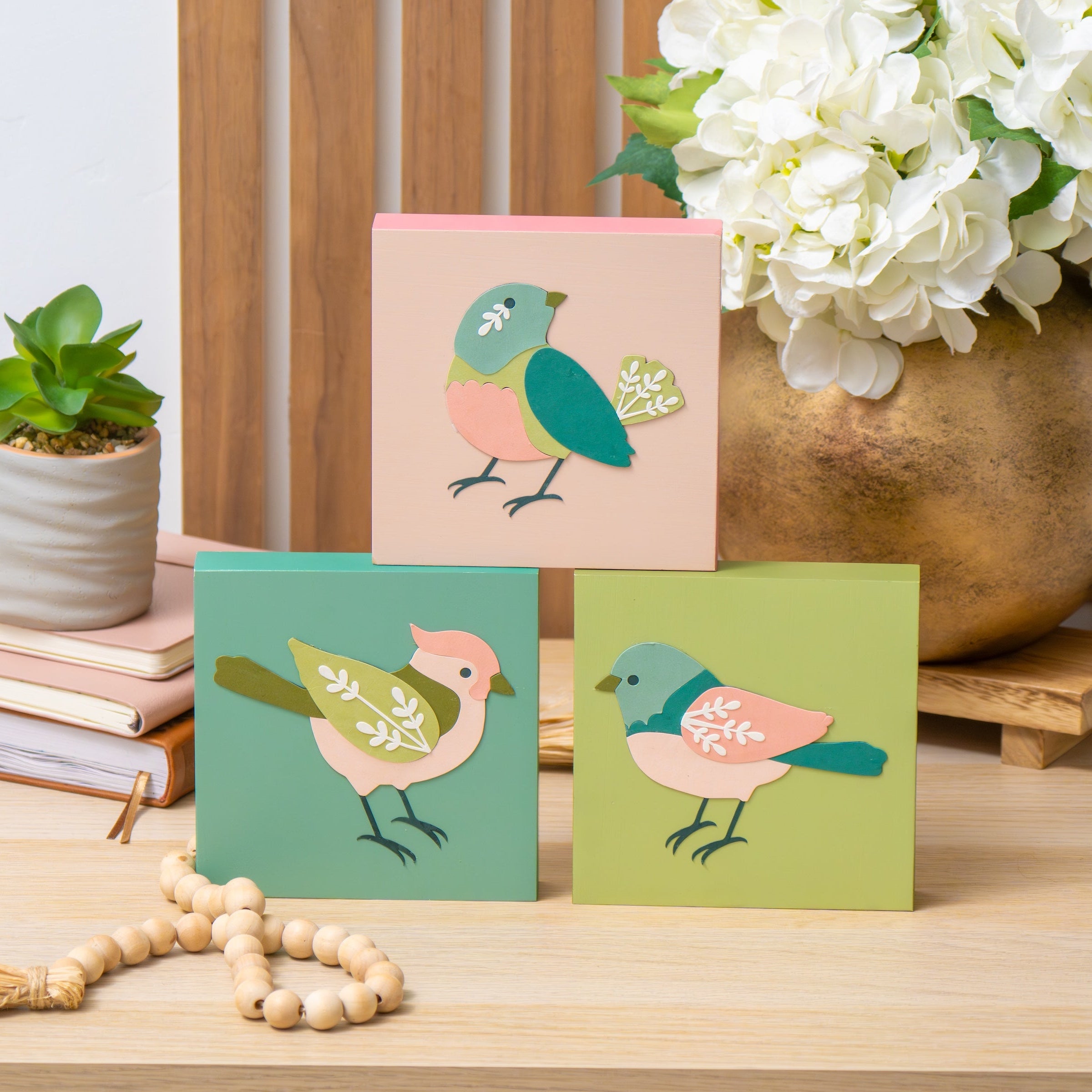 colorful paper bird craft displayed on a table with flowers and books