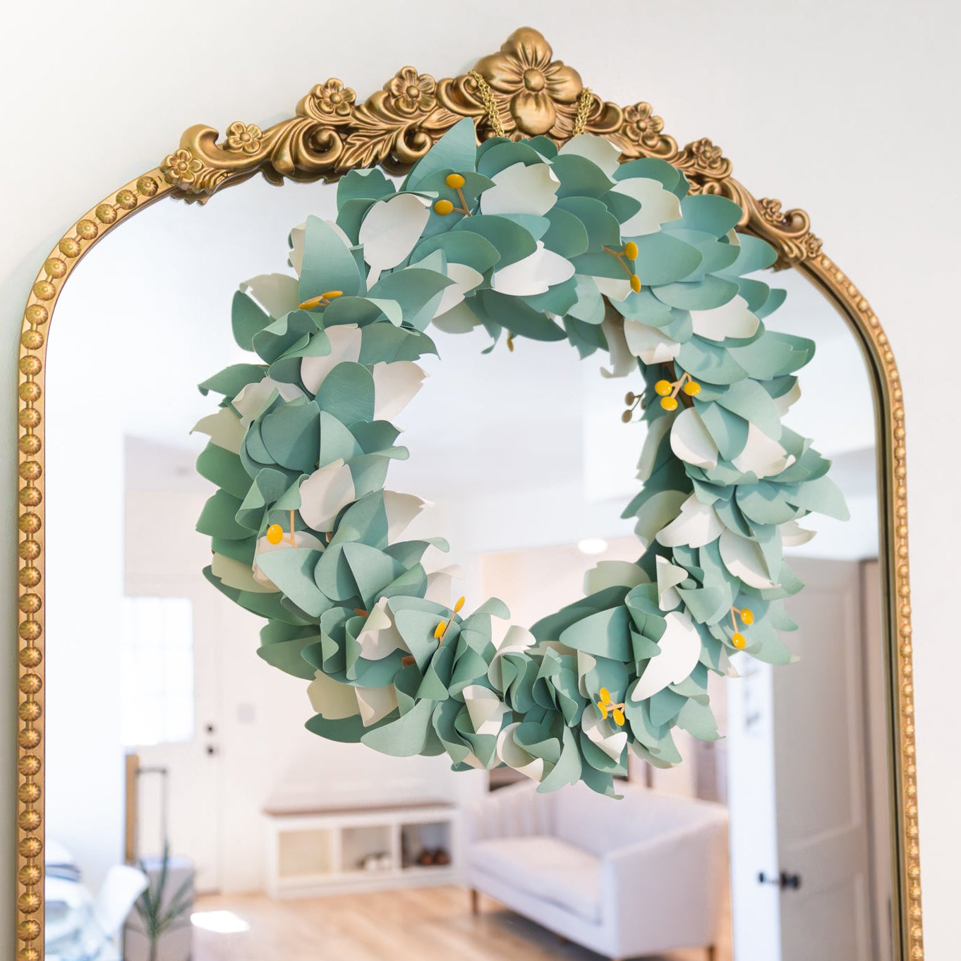 Decorative wreath on a large ornate mirror with a room in the background