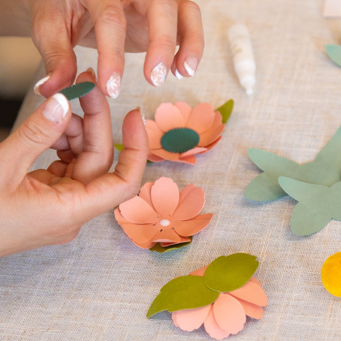 Hands arranging colorful paper flowers for a DIY garland