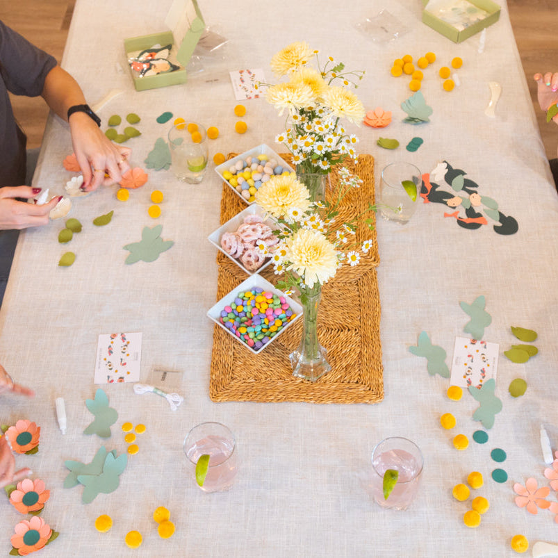 Four adult women sitting around a table with paper craft kits having a craft party