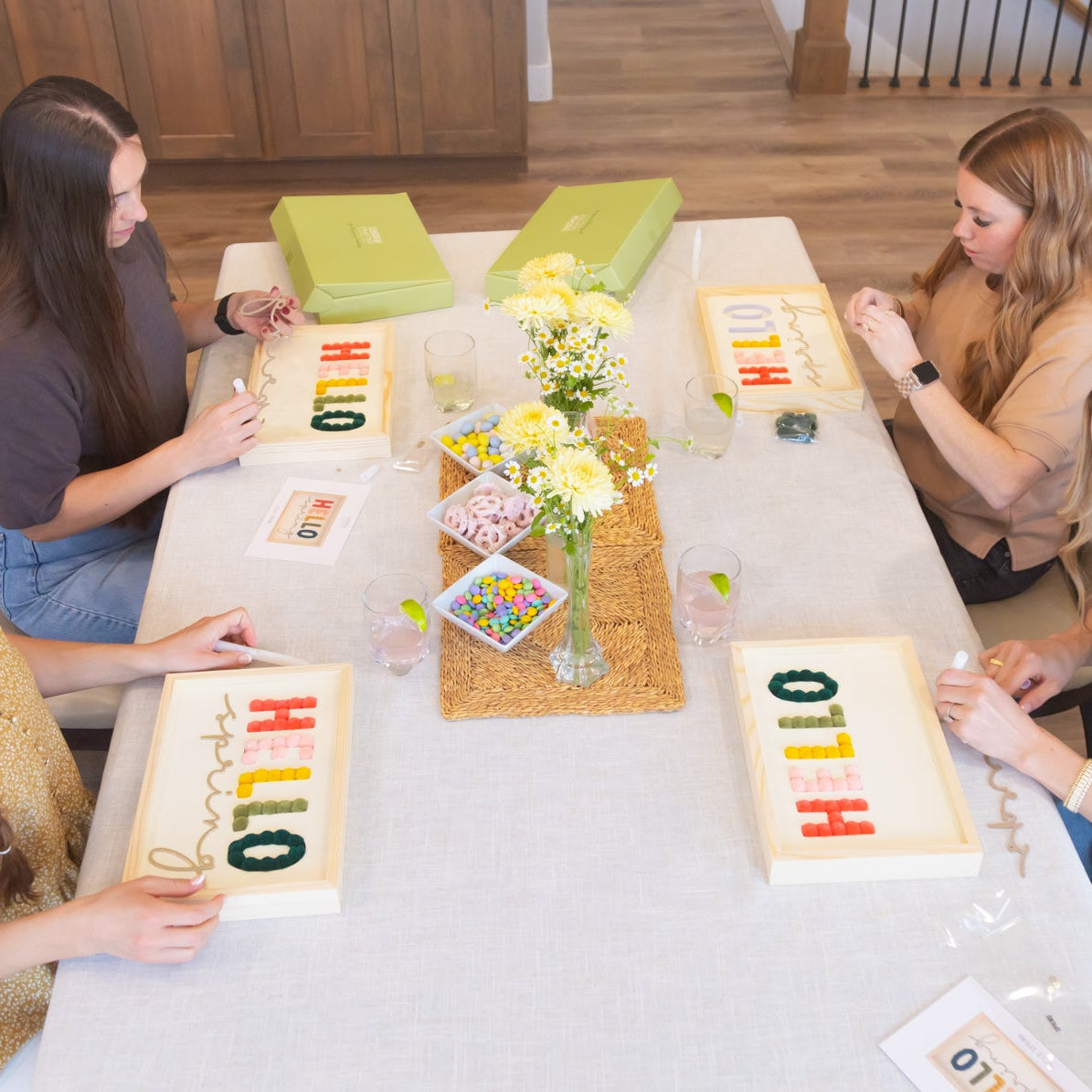 Four women sitting around a table with colorful letter boards having a craft party