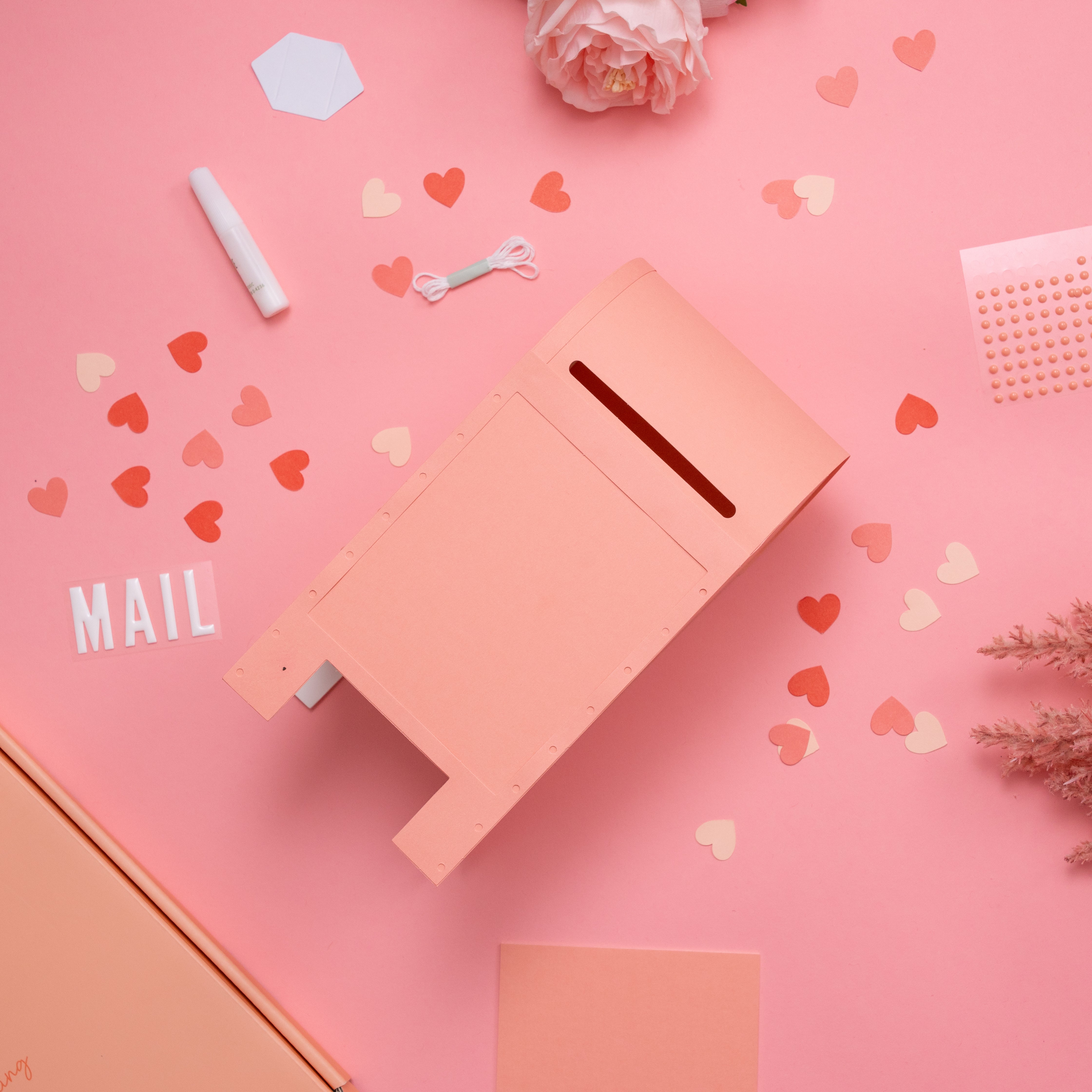 Pink mailbox craft on a pink background with heart shapes and the word 'MAIL'.