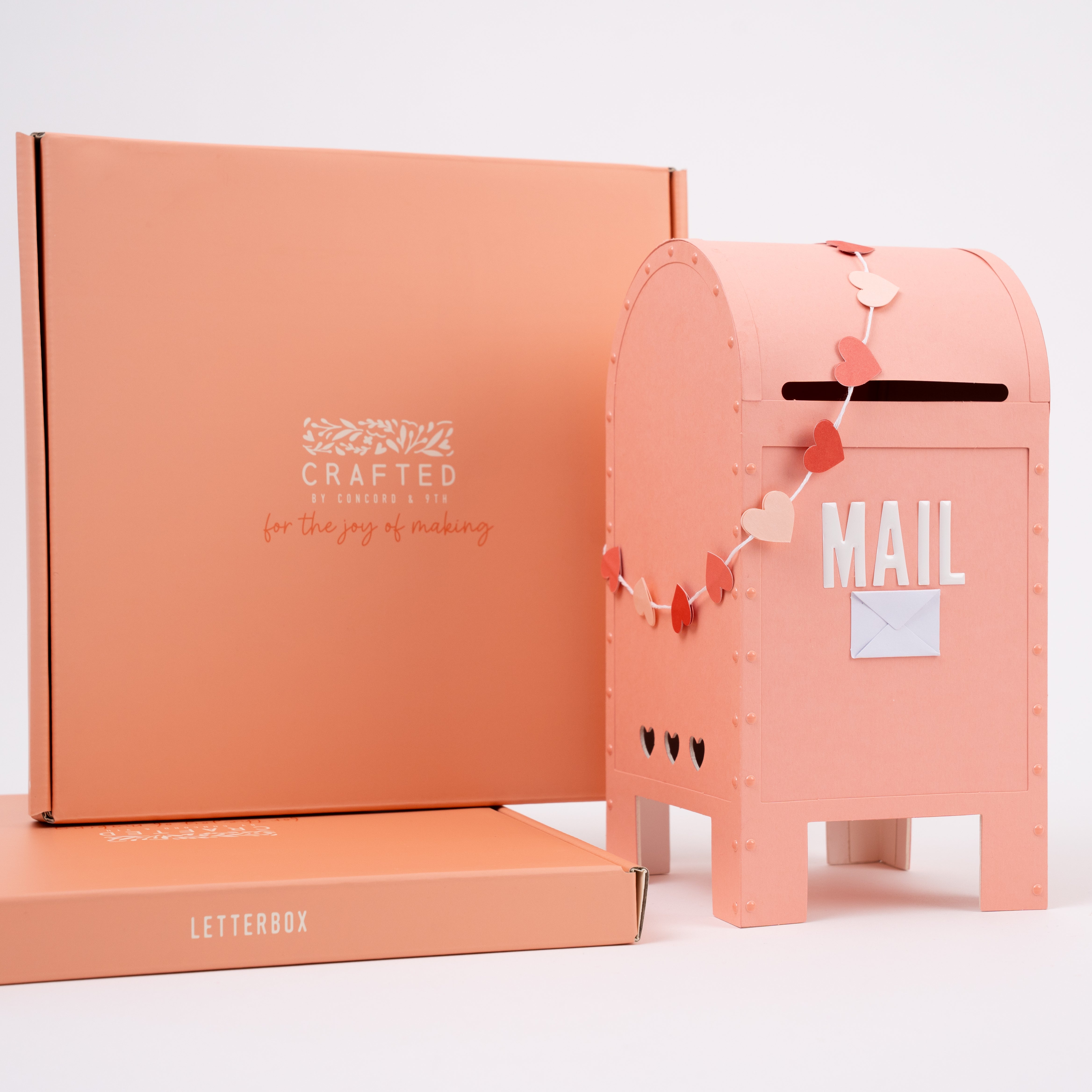 Pink mailbox with decorative elements and packaging box on a white background