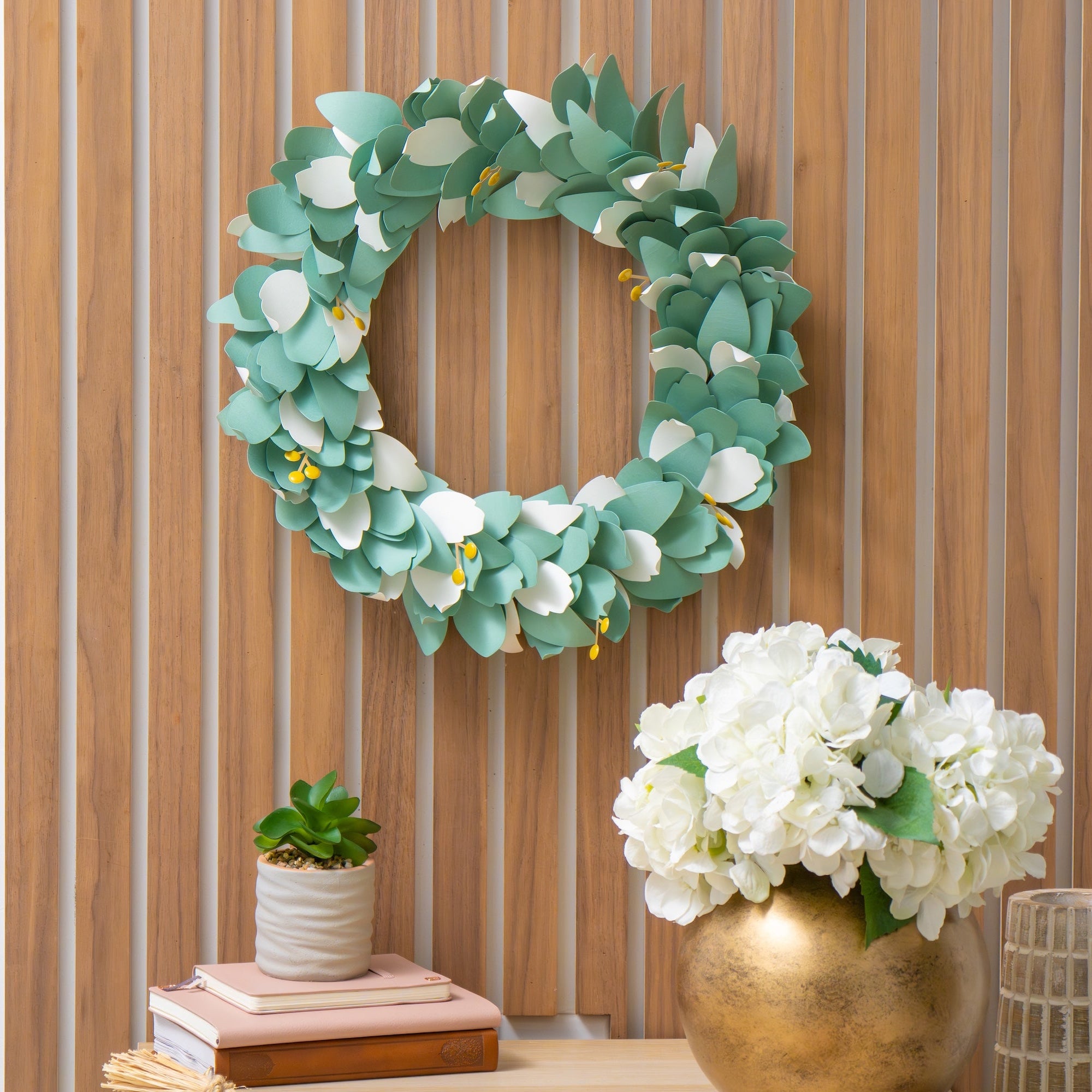 diy paper wreath displayed on a wall above decorative shelf