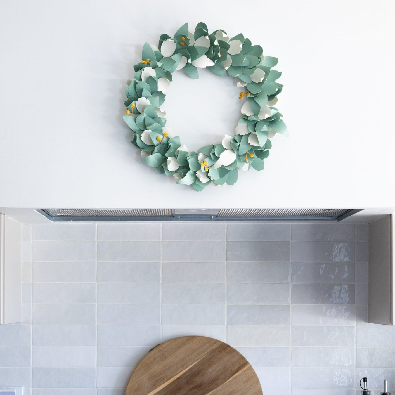 Kitchen with a decorative diy paper wreath on the wall above a cutting board.