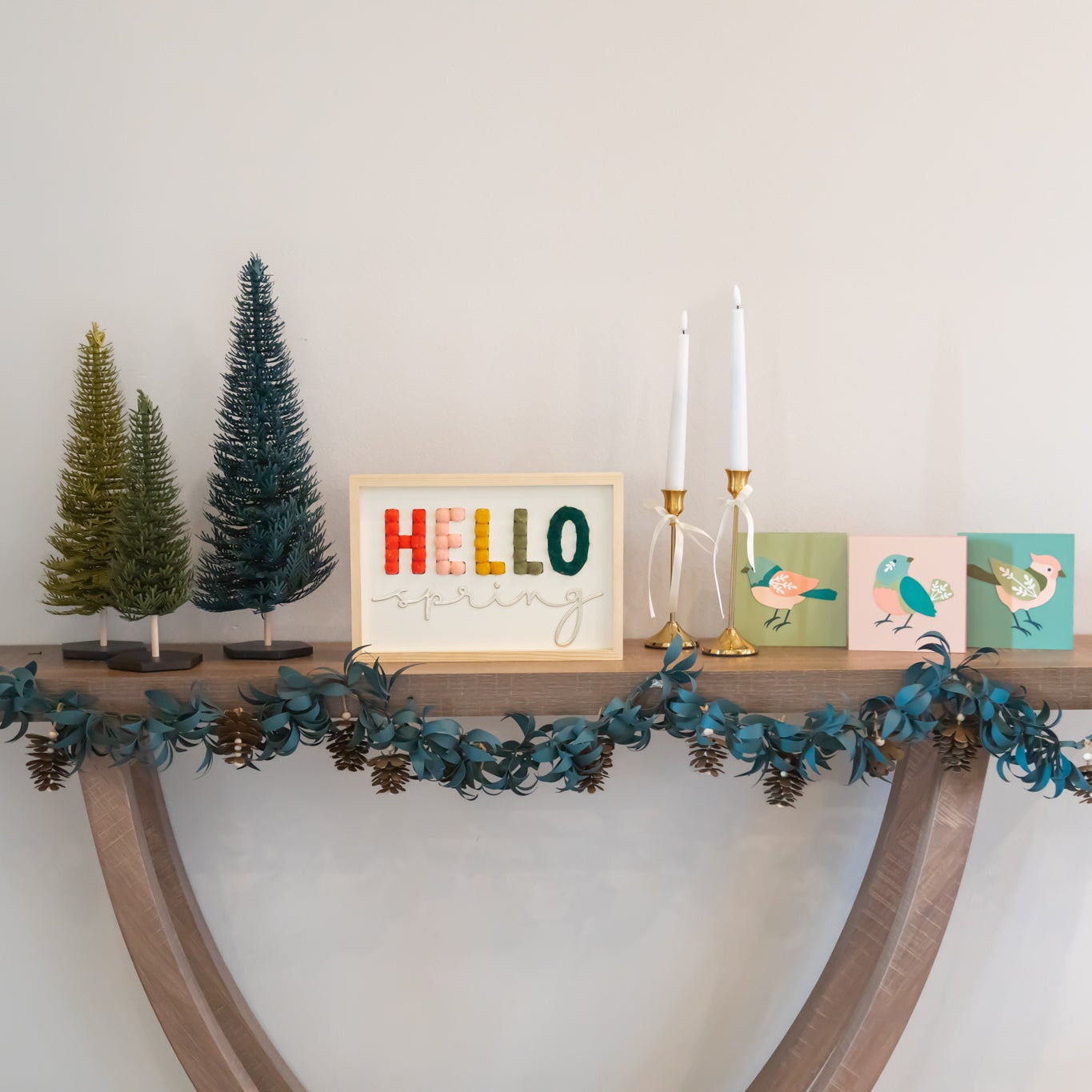 paper crafted trees, 'HELLO Spring' sign, and bird blocks on a shelf as home decor.