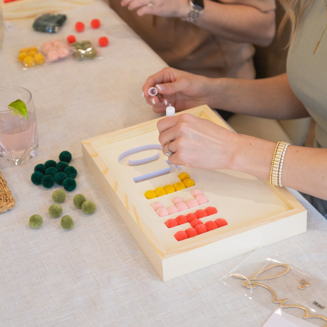 Person arranging colorful letters on a spring sign during a craft party for adult women
