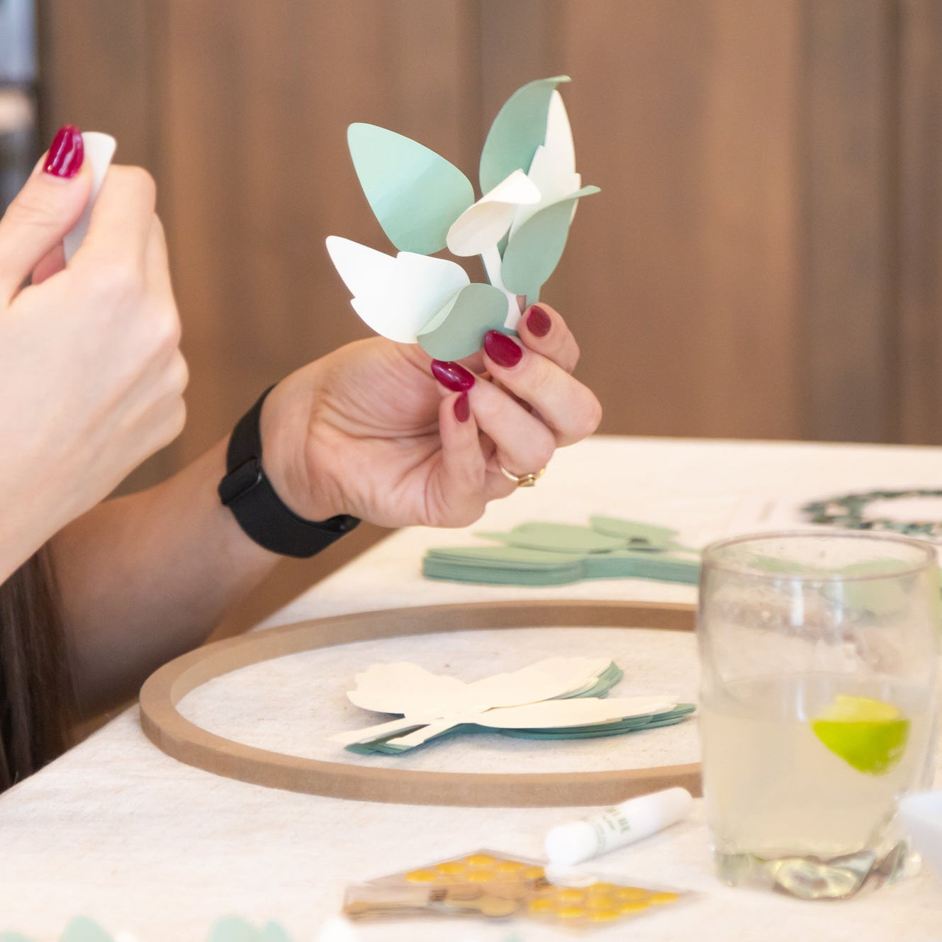 Person holding a curled paper leaves while making a DIY paper wreath