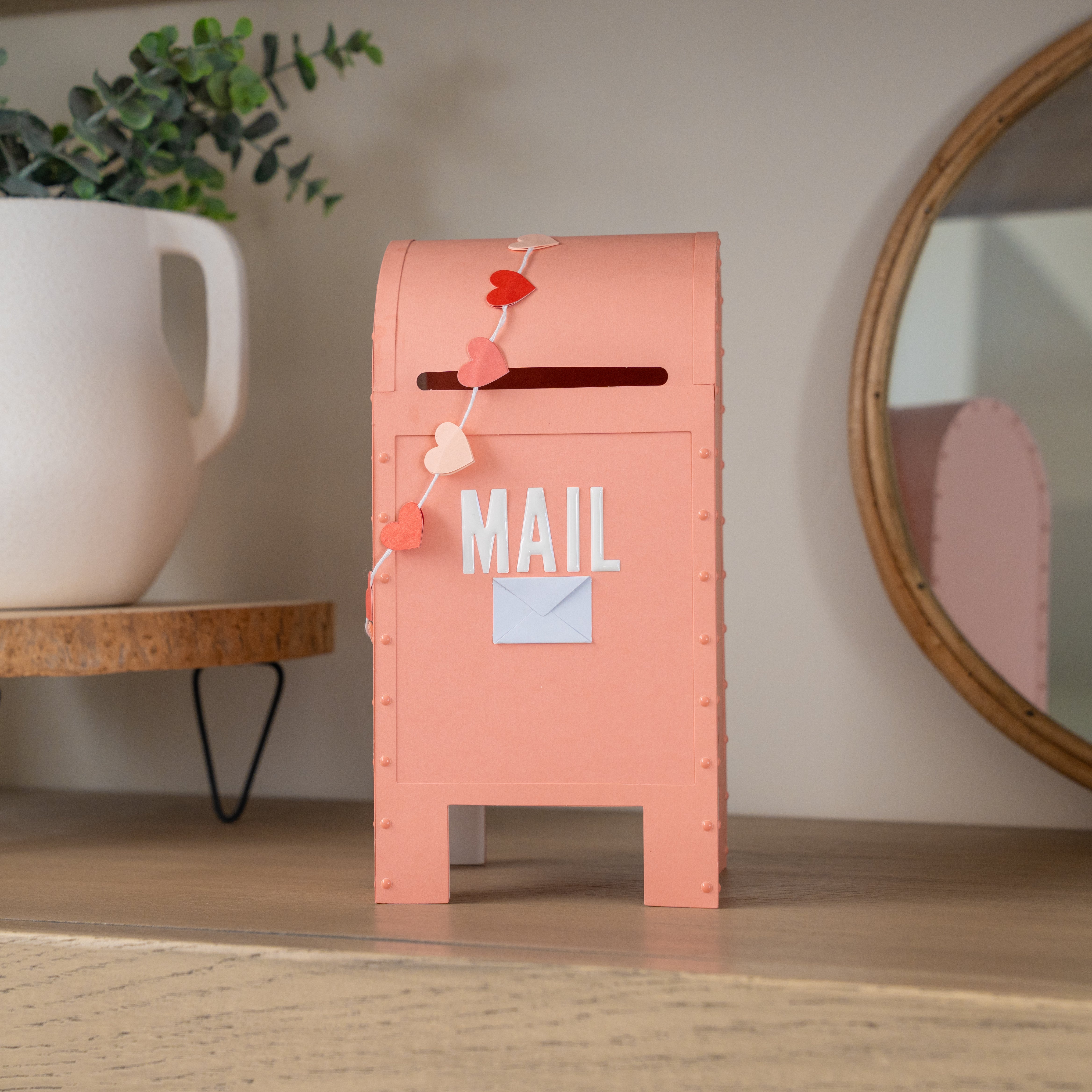 Pink mailbox DIY with decorative elements on a wooden surface.